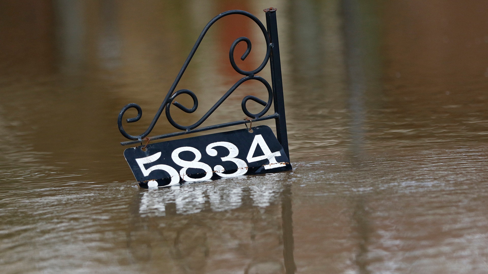 A house address sign floats as water from the Pearl River floods this Jackson, Miss., neighborhood Sunday.