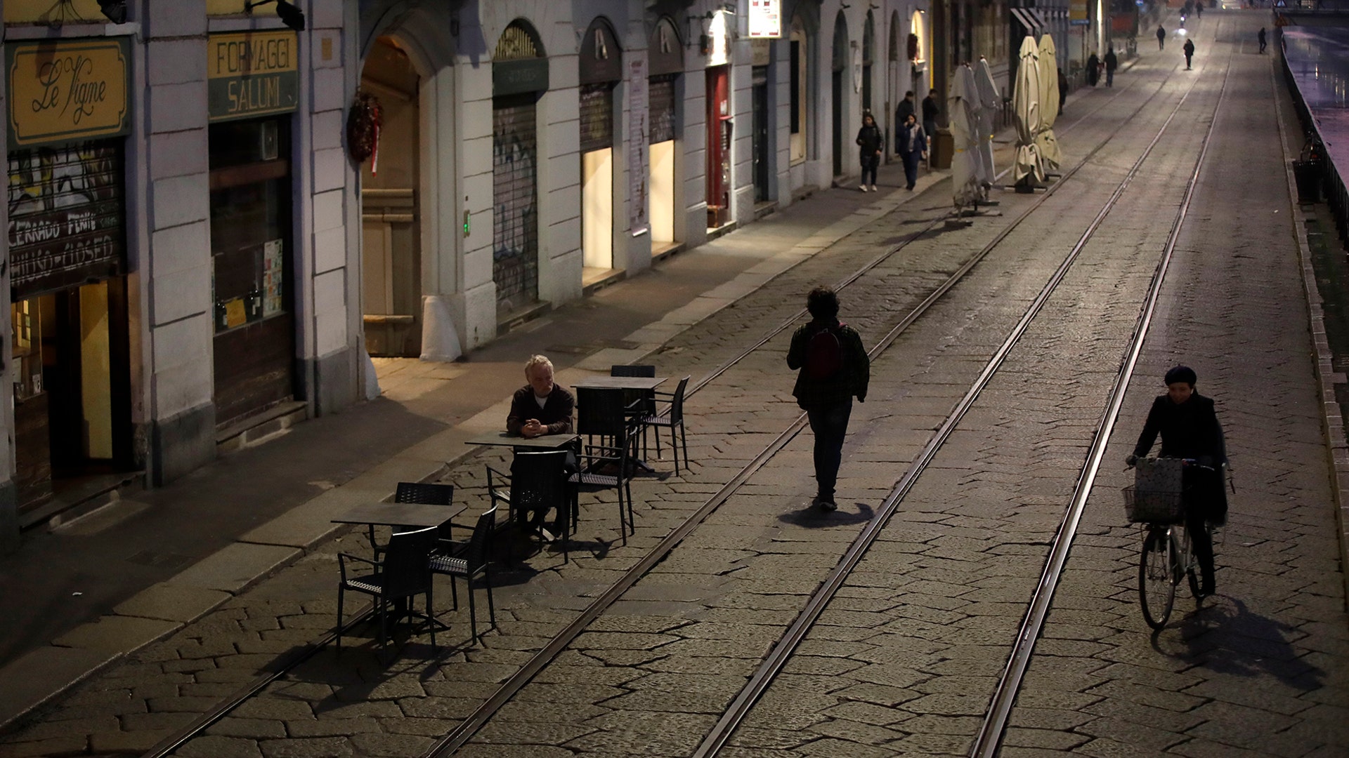 A man sits alone outside a bar at the Naviglio Grande canal in Milan, Italy, Feb. 24, 2020.