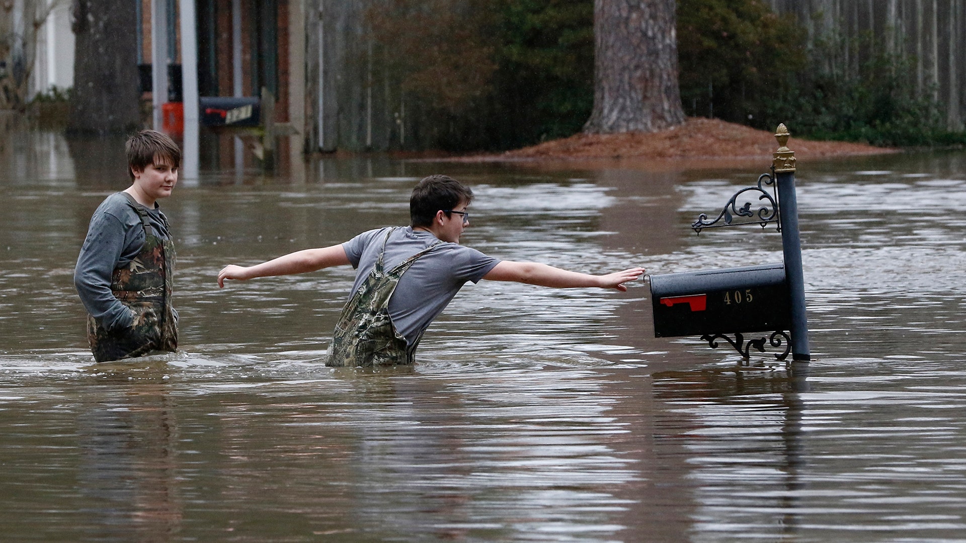 Blaine Henderson reaches for a mailbox as he and his friend Jonah Valdez play in the floodwaters of the Pearl River in Jackson, Mississippi, Feb. 16, 2020.