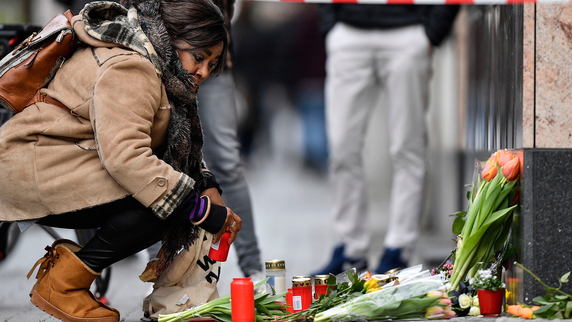 A woman sets a candle near the hookah bar scene where several people were killed late Wednesday in Hanau, Germany, Feb. 20, 2020.
