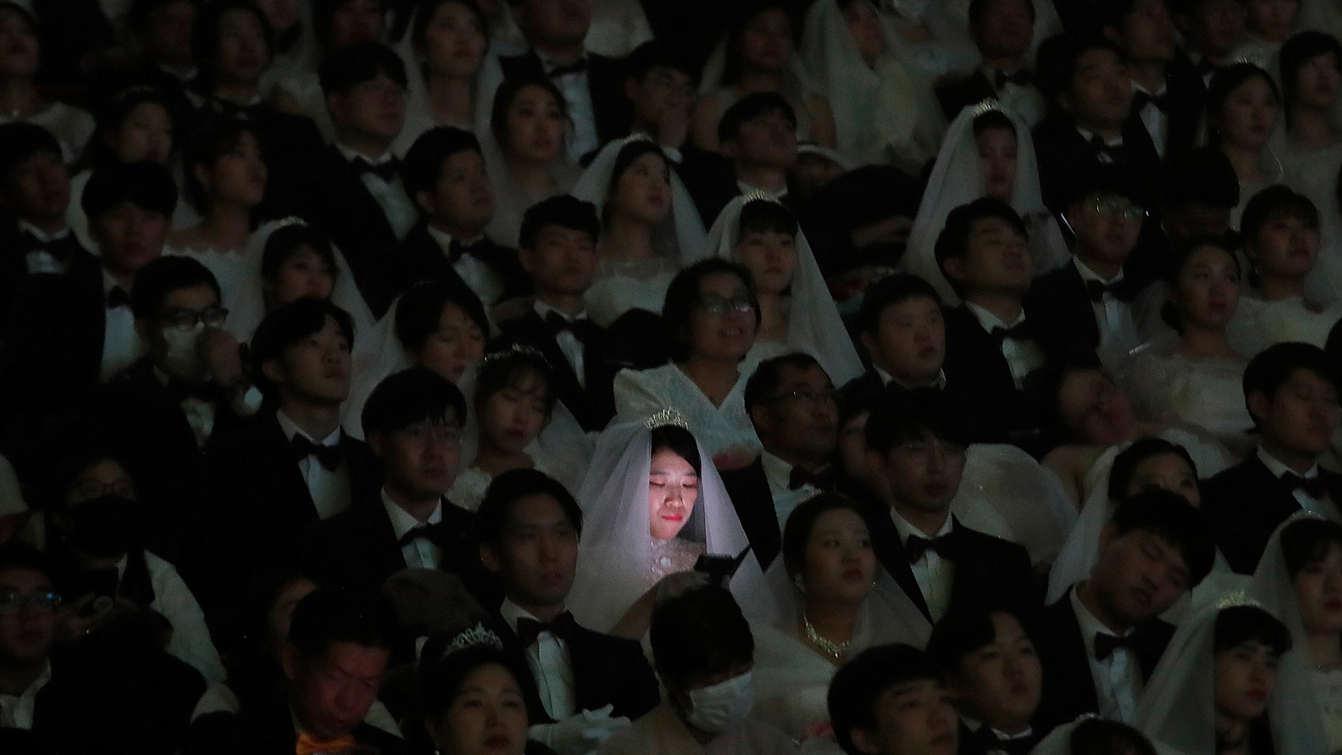 A bride watches her smartphone in a mass wedding ceremony at the Cheong Shim Peace World Center in Gapyeong, South Korea, Feb. 7, 2020.