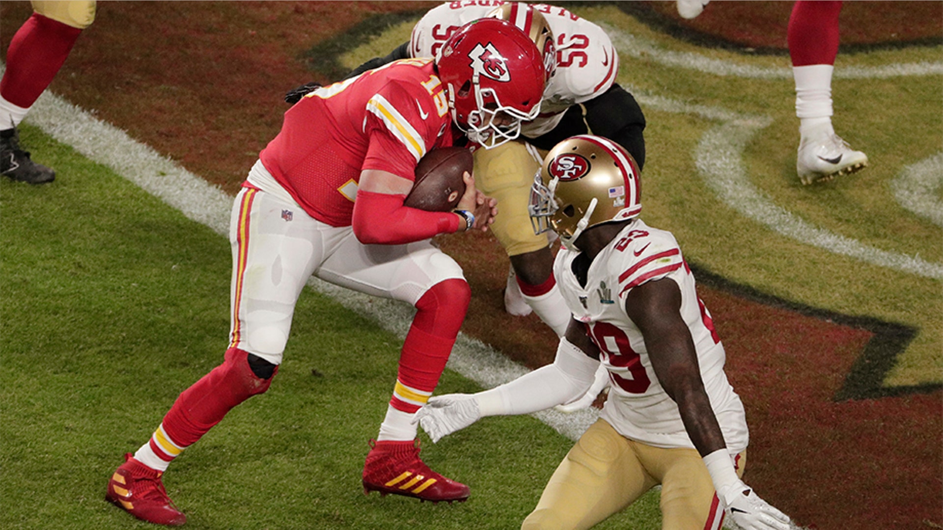 Kansas City Chiefs quarterback Patrick Mahomes (15) scores a touchdown as Kansas City Chiefs' Ben Niemann (56) attempts to tackle him, during the first half of the game. To the right is Kansas City Chiefs' Kendall Fuller (29).