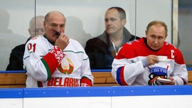 Vladimir Putin enjoys a drink during hockey match with Belarus' president