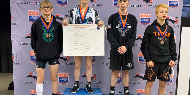 This photo provided by North Carolina High School Athletic Association (NCHSAA) shows Heaven Fitch, center, Luke Wilson, left, and Hunter Fulp, right, and Brandon Ropp, far right, after the state wrestling championships in Greensboro, N.C, on Saturday, Feb. 22, 2020.