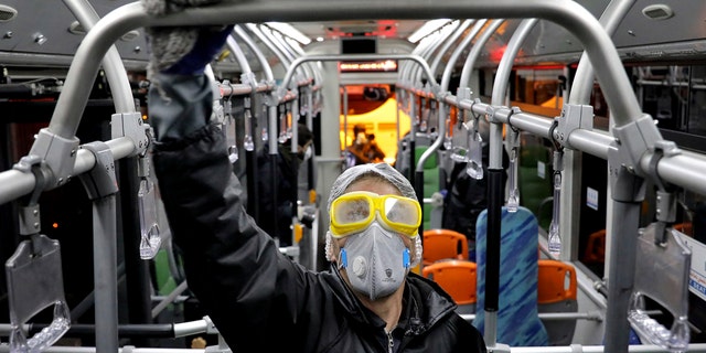 A worker disinfects a public bus against coronavirus in Tehran, Iran, in early morning of Wednesday, Feb. 26, 2020. Iran's government said Tuesday that more than a dozen people had died nationwide from the new coronavirus, rejecting claims of a much higher death toll of 50 by a lawmaker from the city of Qom that has been at the epicenter of the virus in the country. 