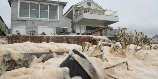 Sea foam brought by waves approaches on beach front houses after heavy rain and storms at Collaroy in Sydney's Northern Beaches, Monday, February 10, 2020.