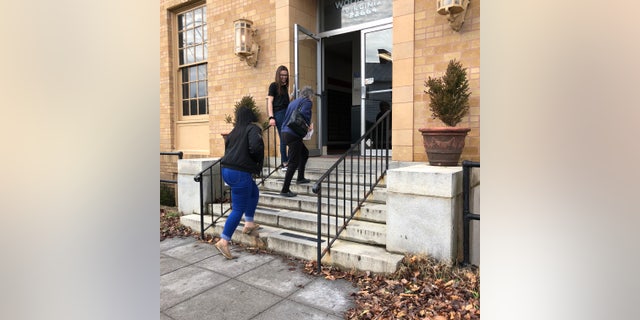 Author Jason F. Wright's daughter Jadi holds the door open for patrons at a Post Office in Virginia.
