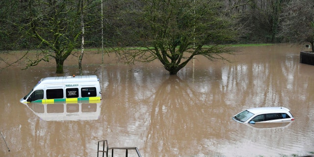 Uma ambulância, à esquerda, e um veículo estão submersos após inundações em Nantgarw, País de Gales, domingo, 16 de fevereiro de 2020.