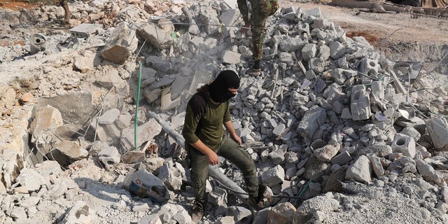 In this Oct. 27, 2019, file photo, people look at a destroyed houses near the village of Barisha, in Idlib province, Syria, after an operation by the U.S. military which targeted Abu Bakr al-Baghdadi, the shadowy leader of the Islamic State group. (AP Photo/Ghaith Alsayed, File)