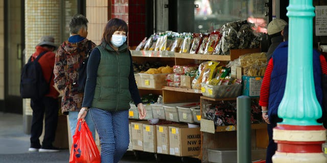 A masked shopper walks in the Chinatown district of San Francisco on Friday, Jan. 31, 2020. As China grapples with the growing coronavirus outbreak, Chinese people in California are encountering a cultural disconnect as they brace for a possible spread of the virus in their adopted homeland. (AP Photo/Ben Margot)