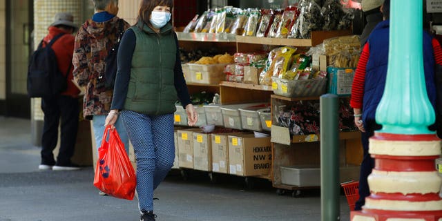 A masked shopper walks in the Chinatown district of San Francisco on Friday, Jan. 31, 2020. As China grapples with the growing coronavirus outbreak, Chinese people in California are encountering a cultural disconnect as they brace for a possible spread of the virus in their adopted homeland. (AP Photo/Ben Margot)