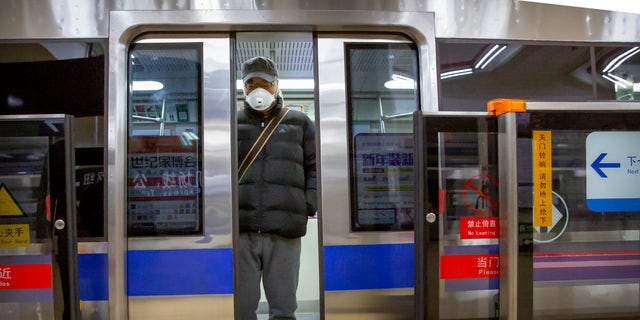 A man wearing a face mask stands on a subway train in Beijing, Monday, Feb. 3, 2020. Much of China officially went back to work on Monday after the Lunar New Year holiday was extended several days by the government due to a virus outbreak, but China's capital remained largely empty as local officials strongly encouraged non-essential businesses to remain closed or work from home. (AP Photo/Mark Schiefelbein)