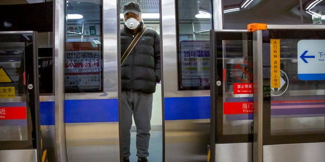 A man wearing a face mask stands on a subway train in Beijing, Monday, Feb. 3, 2020. Much of China officially went back to work on Monday after the Lunar New Year holiday was extended several days by the government due to a virus outbreak, but China's capital remained largely empty as local officials strongly encouraged non-essential businesses to remain closed or work from home. (AP Photo/Mark Schiefelbein)