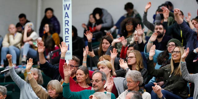 Supporters for Democratic presidential candidate Sen. Elizabeth Warren, D-Mass., raise their hands to be counted during a Democratic party caucus at Hoover High School, Monday, Feb. 3, 2020, in Des Moines, Iowa. (AP Photo/Charlie Neibergall)