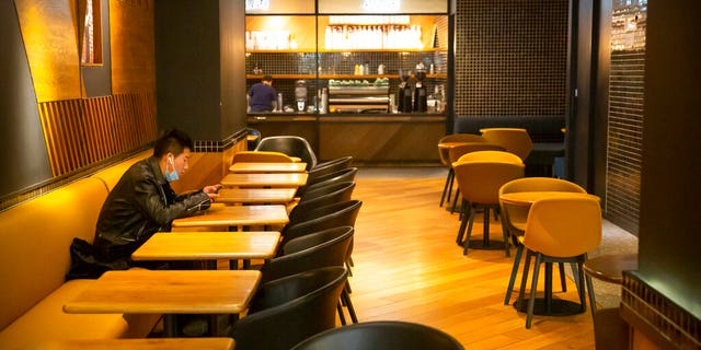 FILE: A man wearing a face mask waits for his food at an empty restaurant in Beijing. (AP Photo/Mark Schiefelbein, File)