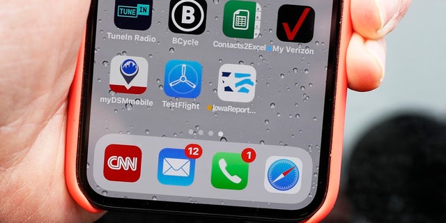 Precinct captain Carl Voss, of Des Moines, Iowa, holds his iPhone that shows the Iowa Democratic Party's caucus reporting app icon on Tuesday in Des Moines, Iowa. (AP Photo/Charlie Neibergall)