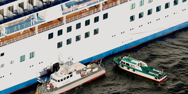 Japan Coast Guard's patrol boat, left, is brought alongside the cruise ship Diamond Princess to take passengers tested positive for coronavirus to hospitals off Yokohama, south of Tokyo, Wednesday, Feb. 5, 2020.  (Hiroko Harima/Kyodo News via AP)