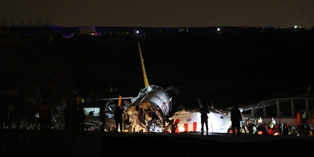 Rescue members working after the plane skidded off the runway in Istanbul. (AP)