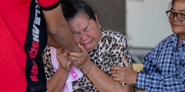 A relative of a victim in the mass shooting is comforted outside the emergency room iwhere victims are being treated in Korat, Nakhon Ratchasima, Thailand, Sunday, Feb. 9, 2020. (Associated Press)