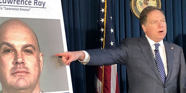 Former U.S. Attorney Geoffrey Berman points to a photo showing Lawrence Ray during a news conference, Tuesday, Feb. 11, 2020, in New York.   College.