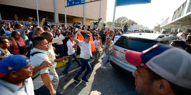 Supporters of Venezuela's President Nicolas Maduro attack a vehicle carrying opposition leader Juan Guaido after he arrived at the Simon Bolivar International Airport in La Guaira, Venezuela, Tuesday, Feb. 11, 2020. Guaido returned home from a tour of nations that back his effort to oust socialist leader Nicolas Maduro. (AP Photo/Matias Delacroix)