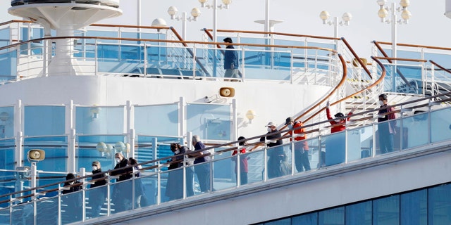 Passengers stand on the deck of the Diamond Princess cruise ship anchored at Yokohama Port. (Yuta Omori/Kyodo News via AP)
