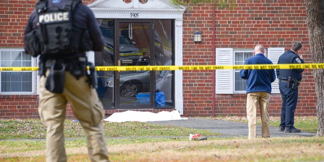 Law enforcement personnel work at the scene which appears to show a body covered under a white blanket outside of an apartment, Wednesday, Feb. 12, 2020, in Baltimore.