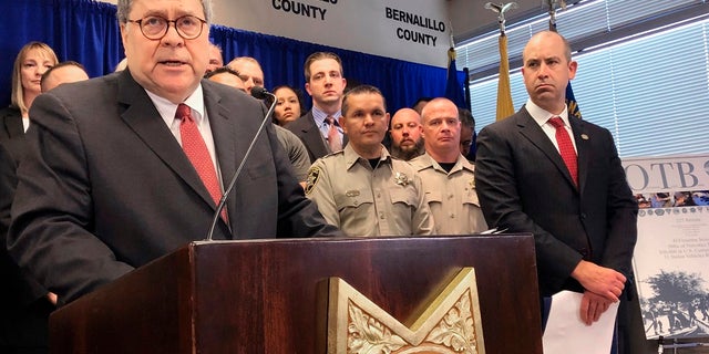 In this Nov. 12, 2019, file photo, U.S. Attorney General William Barr, left, stands with other federal and officials at a news conference at the office of the Bernalillo County Sheriff in Albuquerque, N.M. New Mexico's most populous city stands to lose out on millions of dollars in crime-fighting grants due to its status as a sanctuary city, but some elected officials said Wednesday the U.S. Justice Department is holding out the promise of more federal funding to get Albuquerque to reconsider policies that prevent the sharing of information with federal immigration authorities. (AP Photo/Mary Hudetz, File)
