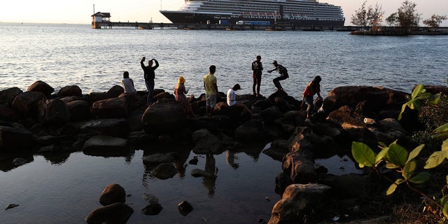 Locals come down to view the Westerdam cruise ship, owned by Holland America Line, docked at the port of Sihanoukville, Cambodia. The Westerdam, turned away by four Asian and Pacific governments due to virus fears, anchored Thursday off Cambodia for health checks on its 2,200 passengers and crew. (AP Photo/Heng Sinith)