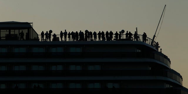 Passengers and crew stand on the railing of the Westerdam cruise ship as it docks at the port of Sihanoukville, Cambodia, Thursday. The Westerdam, turned away by four Asian and Pacific governments due to virus fears, anchored Thursday off Cambodia for health checks on its 2,200 passengers and crew. (AP Photo/Heng Sinith)