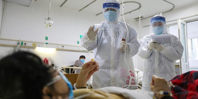Medical workers check on the conditions of patients in Jinyintan Hospital, designated for critical COVID-19 patients, in Wuhan.(Chinatopix Via AP)