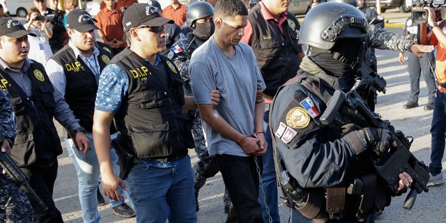 Police officers escort prison escapee Gilberto Ventura Ceballos, center, to the police headquarters in Panama City, Thursday, Feb. 13, 2020. (AP Photo/Arnulfo Franco)