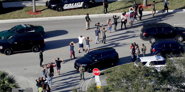 Feb. 14, 2018: Students hold their hands in the air as they are evacuated by police from Marjory Stoneman Douglas High School in Parkland, Fla., after a shooter opened fire on the campus. (Mike Stocker/South Florida Sun-Sentinel via AP, File)