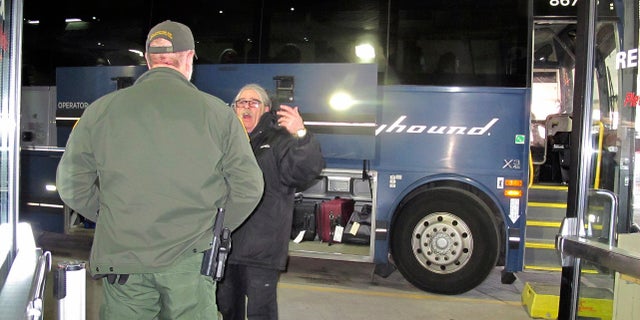 A worker, right, speaks with a Customs and Border Protection agent seeking to board a Greyhound bus headed for Portland, Ore., at the Spokane Intermodal Center, a terminal for buses and Amtrak in Spokane, Wash. (AP Photo/Nicholas K. Geranios)