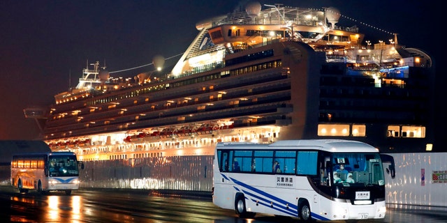 Buses carrying U.S. passengers who were aboard the quarantined cruise ship the Diamond Princess, seen in the background. (Jun Hirata/Kyodo News via AP)