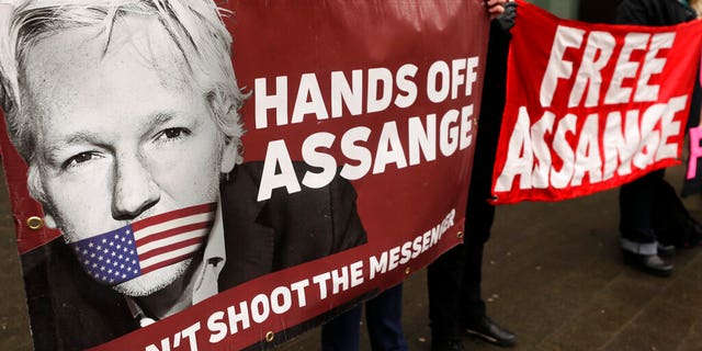 Demonstrators hold banners outside Westminster Magistrates Court in London, Wednesday, Feb. 19, 2020.