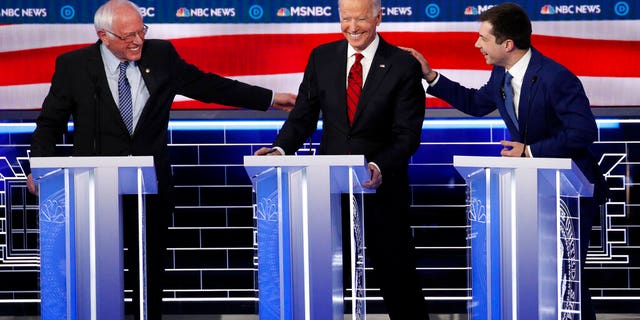 Democratic presidential candidates Sen. Bernie Sanders, I-Vt., left, and former South Bend Mayor Pete Buttigieg, right, reach for former Vice President Joe Biden during a Democratic presidential primary debate Wednesday, Feb. 19, 2020, in Las Vegas, hosted by NBC News and MSNBC. (AP Photo/John Locher)