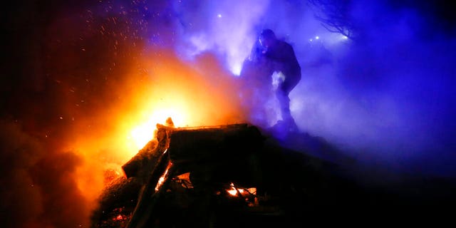 A protester, who planned to stop buses carrying passengers evacuated from the Chinese city of Wuhan, kindles a fire outside Novi Sarzhany, Ukraine, Thursday, Feb. 20, 2020.