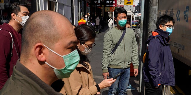 People wearing face masks walk on a down own street in Hong Kong Friday, Feb. 21, 2020. COVID-19 viral illness has sickened tens of thousands of people in China since December. (Associated Press)