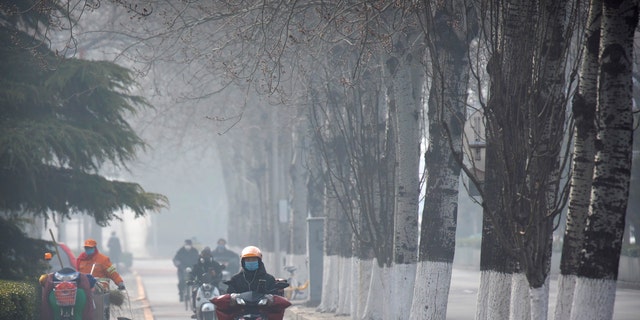 People wear face masks as they ride along a road in Beijing, Friday, Feb. 21, 2020. (Associated Press)