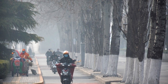 People wear face masks as they ride along a road in Beijing, Friday, Feb. 21, 2020. (Associated Press)