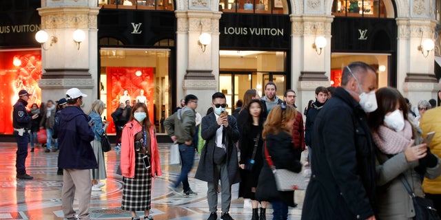 Tourists wearing sanitary masks walk in downtown Milan, Italy, Sunday, Feb. 23, 2020. In Lombardy, the hardest-hit region with 90 cases Coronavirus infections, schools and universities were ordered to stay closed in the coming days, and sporting events were canceled. (AP Photo/Antonio Calanni)