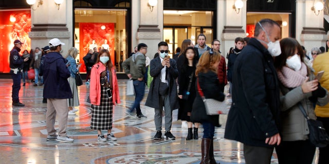 Tourists wearing sanitary masks walk in downtown Milan, Italy, Sunday, Feb. 23, 2020. In Lombardy, the hardest-hit region with 90 cases Coronavirus infections, schools and universities were ordered to stay closed in the coming days, and sporting events were canceled. (AP Photo/Antonio Calanni)