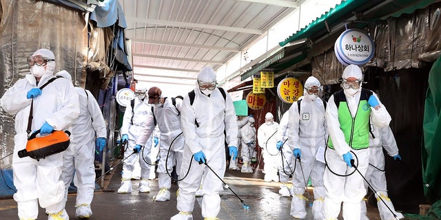 Workers wearing protective suits spray disinfectant as a precaution against the coronavirus at a market in Bupyeong, South Korea, on Monday. South Korea reported another large jump in new virus cases Monday a day after the president called for "unprecedented, powerful" steps to combat the outbreak that is increasingly confounding attempts to stop the spread. (Lee Jong-chul/Newsis via AP)