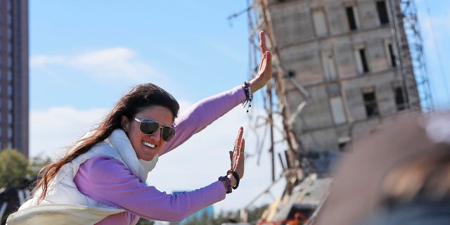 Megan Dority poses for a photo with the so called "Leaning Tower of Dallas" as a crew works to topple the structure north of downtown Dallas, Monday, Feb. 24, 2020.