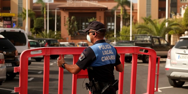 A Spanish police officer sets a barrier blocking access to the H10 Costa Adeje Palace hotel in Tenerife.