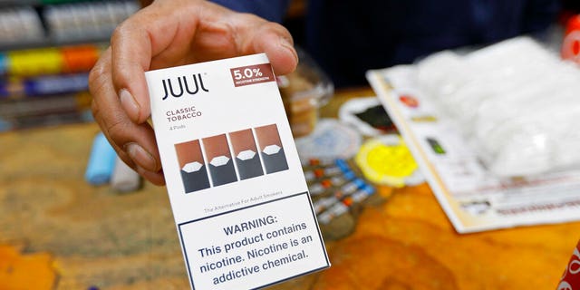In this June 17, 2019, file photo, a cashier displays a packet of tobacco-flavored Juul pods at a store in San Francisco.