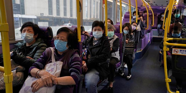 Passengers wears face masks as a precaution against the COVID-19 while sitting in a bus in Hong Kong, Thursday, Feb. 27, 2020. 
