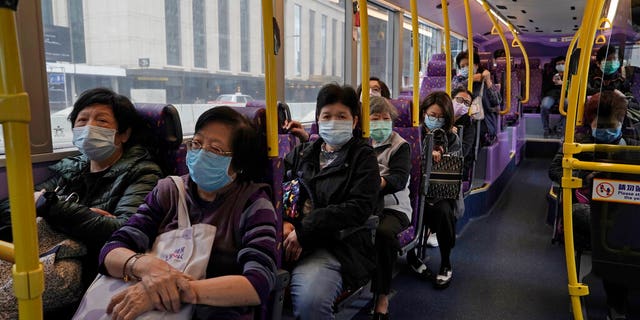 Passengers wears face masks as a precaution against the COVID-19 while sitting in a bus in Hong Kong, Thursday, Feb. 27, 2020. 