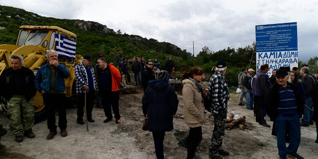 Local residents gather at a roadblock in Karava, on the northeastern Aegean island of Lesbos, Greece, Thursday, Feb. 27, 2020. Greece's government hoped to defuse tensions after protests over plans for new migrant camps on two of its islands Wednesday turned into violent clashes between police and local residents, some armed with Molotov cocktails and shotguns. (AP Photo/Michael Varaklas)
